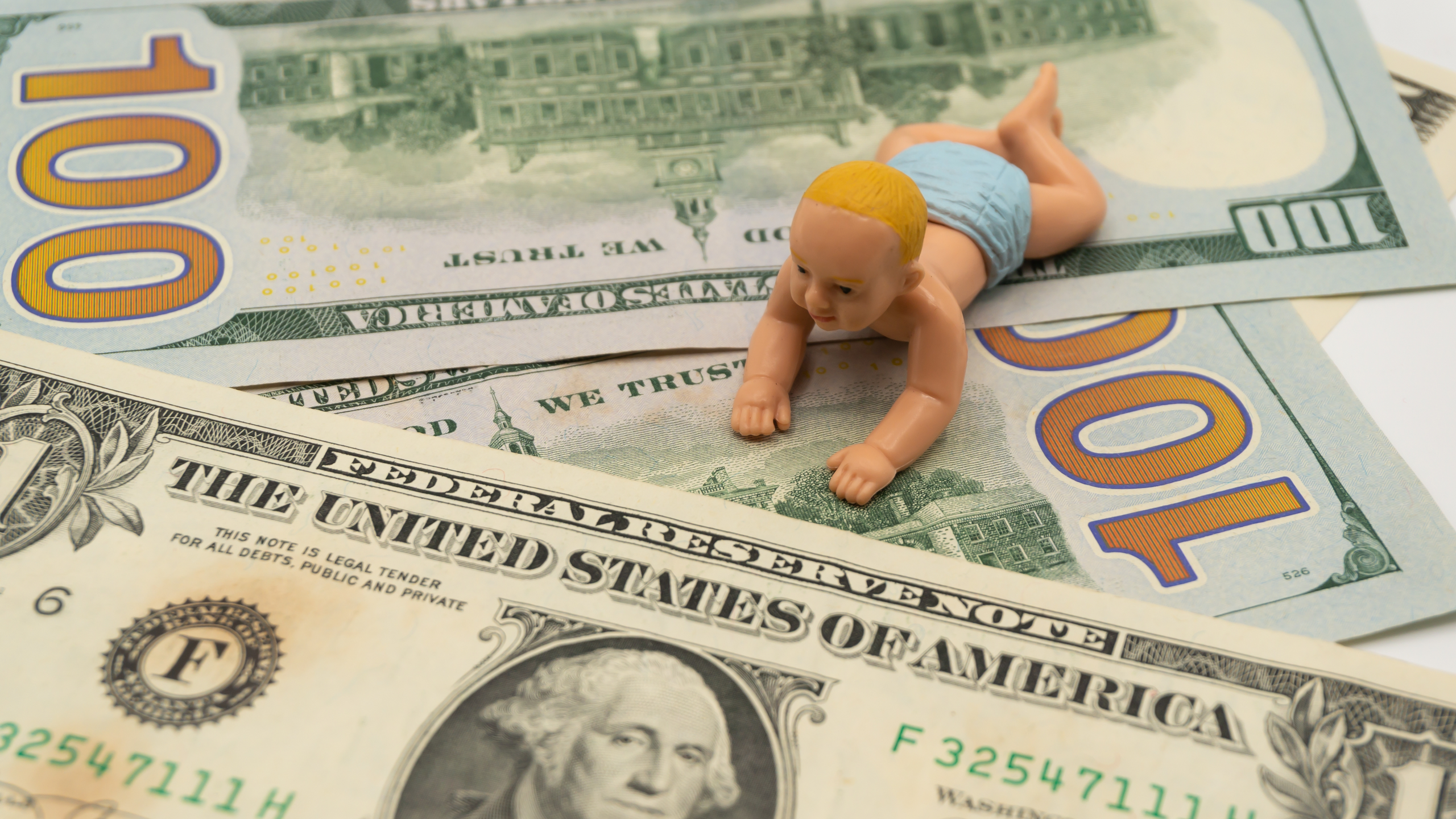 Toy baby laying on top of US dollars